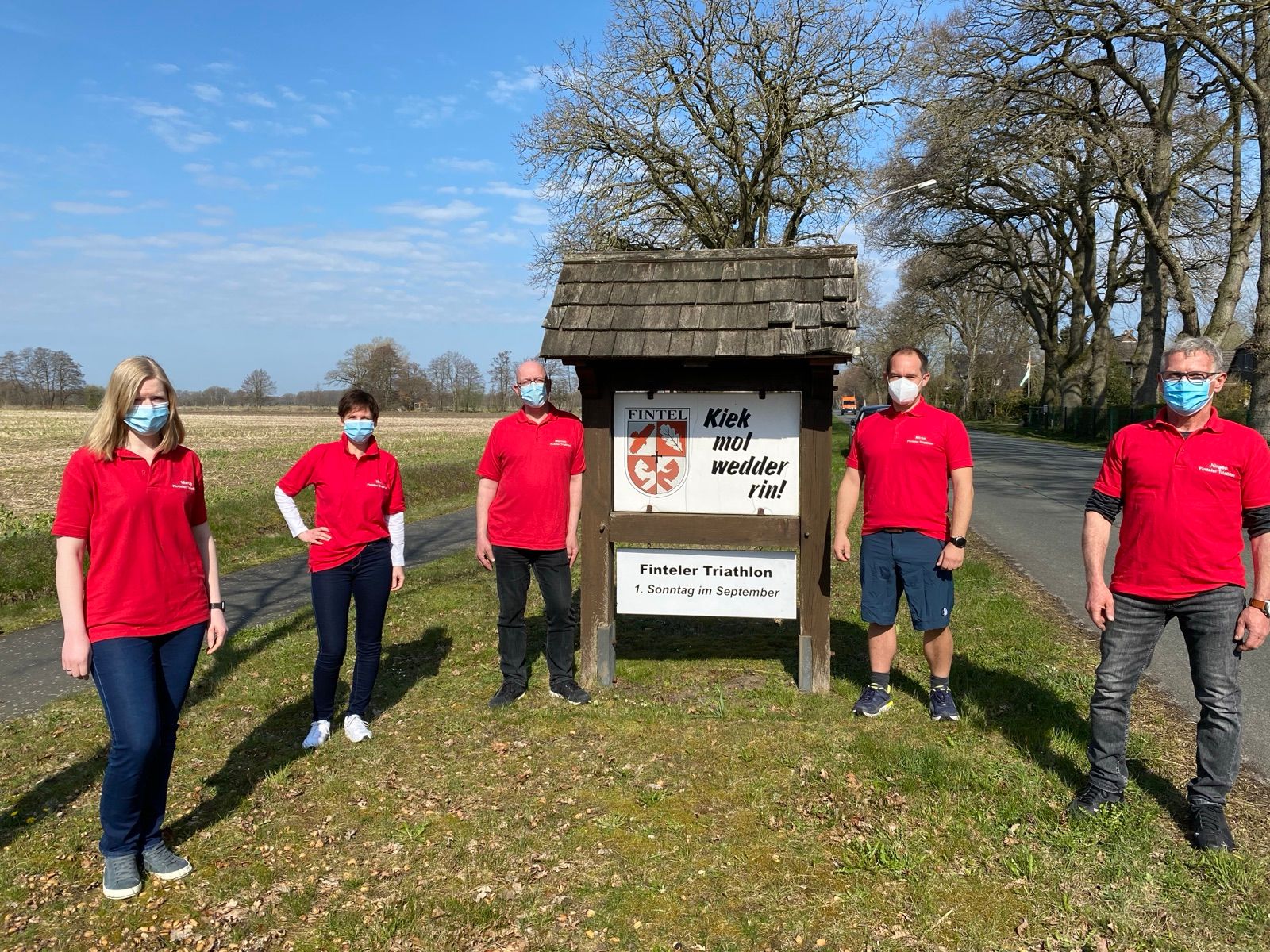 Das Orga-Team mit Masken am Ortseingangsschild von Fintel